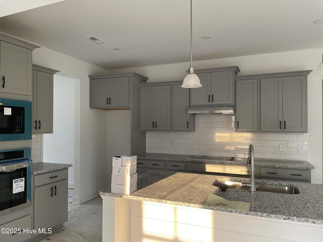 kitchen featuring under cabinet range hood, gray cabinetry, black appliances, and a sink