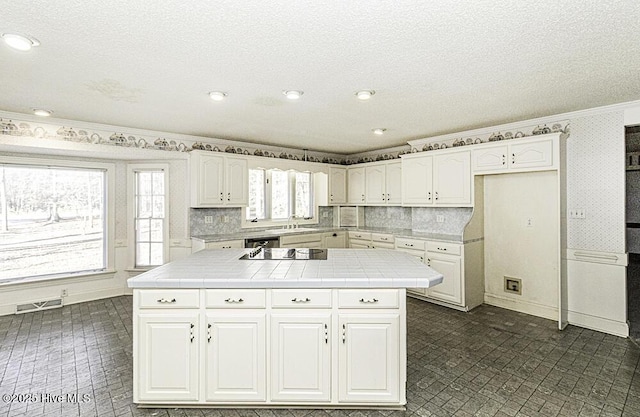 kitchen with backsplash, white cabinetry, and tile counters