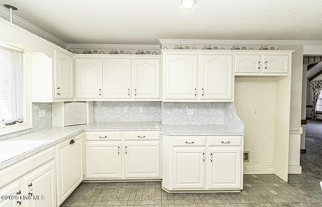 kitchen with white cabinetry, a textured ceiling, and ornamental molding