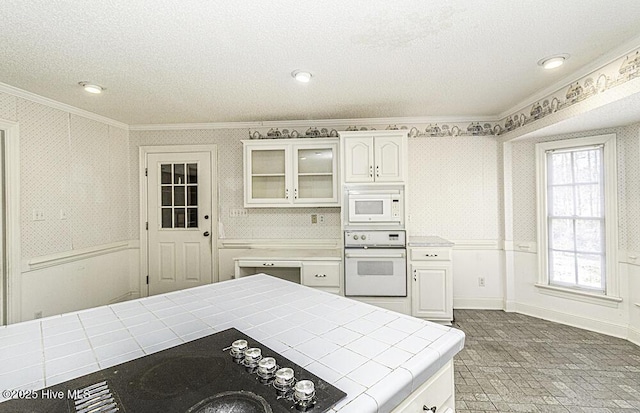 kitchen featuring ornamental molding, a textured ceiling, white appliances, white cabinetry, and tile counters