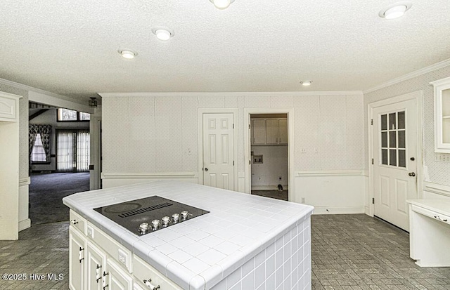 kitchen with black electric stovetop, crown molding, tile countertops, white cabinets, and a center island