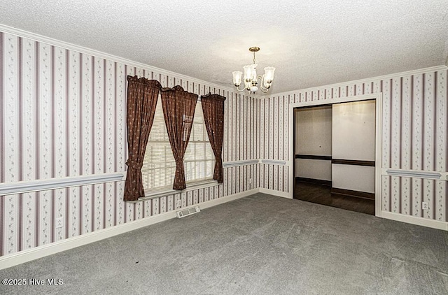 spare room with dark carpet, a textured ceiling, and an inviting chandelier