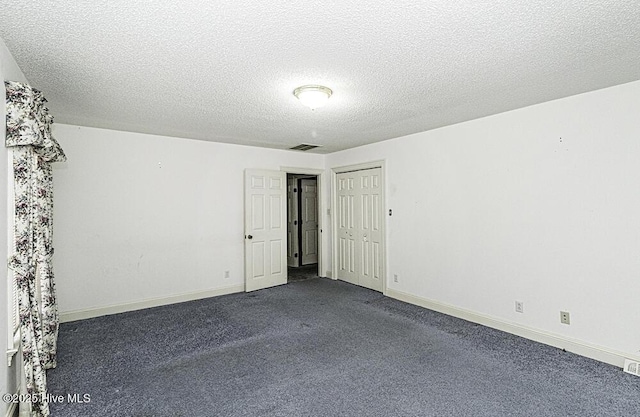 empty room with a textured ceiling and dark colored carpet