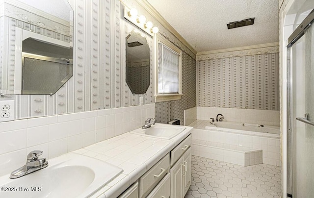 bathroom featuring vanity, tile patterned floors, crown molding, a relaxing tiled tub, and a textured ceiling