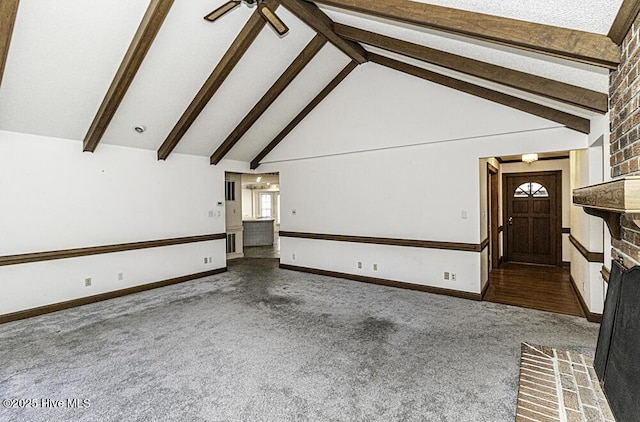 unfurnished living room featuring beamed ceiling, dark carpet, and a fireplace