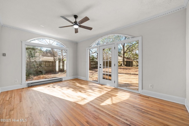 spare room featuring ceiling fan, french doors, a baseboard heating unit, wood-type flooring, and ornamental molding