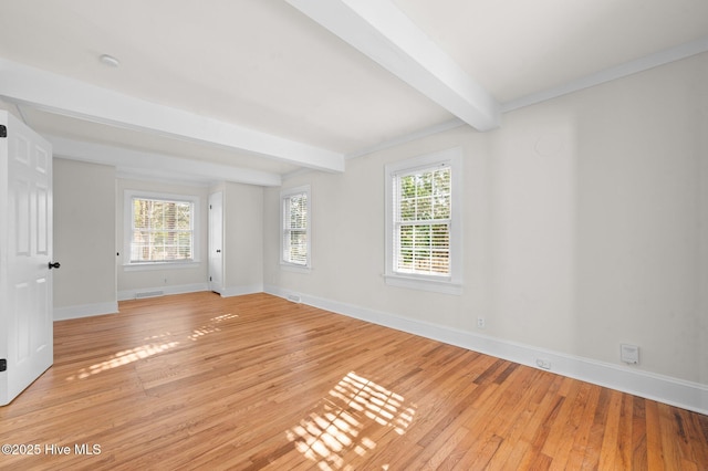 empty room featuring beamed ceiling and light hardwood / wood-style flooring