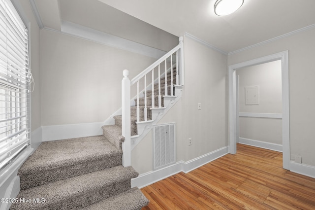 stairs with hardwood / wood-style floors and ornamental molding