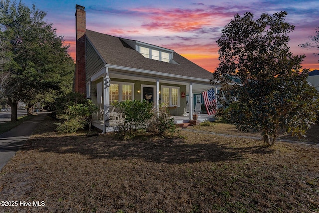 view of front of property with a porch and a yard