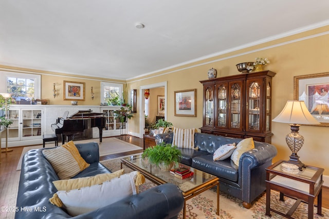 living room featuring wood-type flooring, ornamental molding, and a healthy amount of sunlight