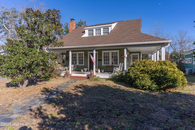 view of front of property with french doors, covered porch, and a front lawn