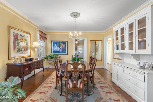 dining area with dark wood-type flooring, ornamental molding, and an inviting chandelier