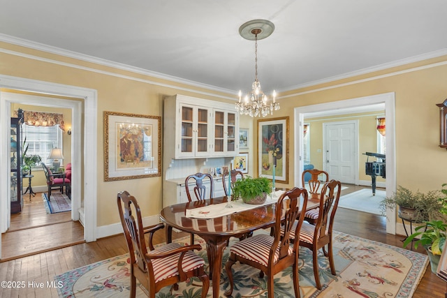 dining area with crown molding, dark hardwood / wood-style floors, and a notable chandelier