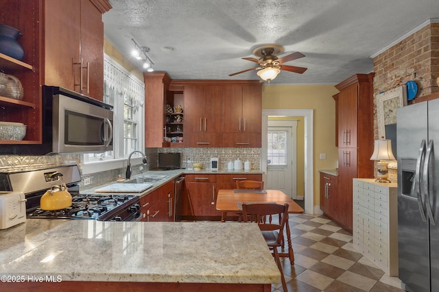 kitchen with sink, light stone counters, a textured ceiling, appliances with stainless steel finishes, and decorative backsplash