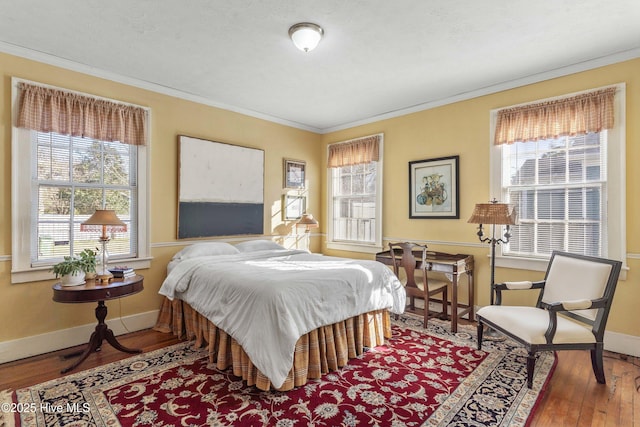 bedroom featuring crown molding, hardwood / wood-style floors, and multiple windows