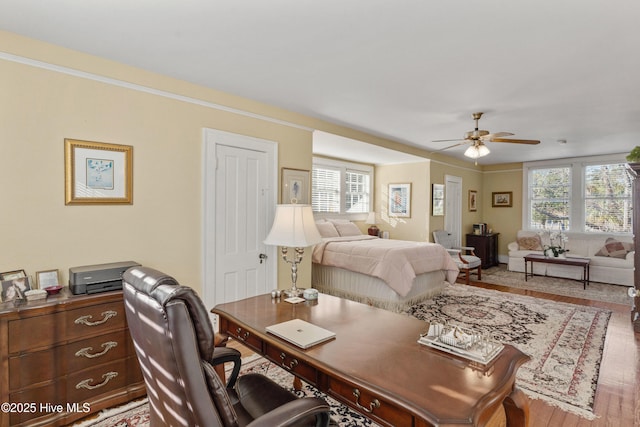 bedroom with hardwood / wood-style floors, ornamental molding, and ceiling fan