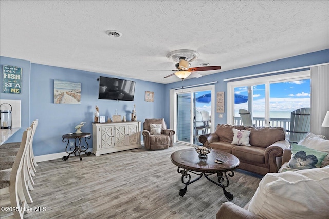 living room featuring ceiling fan, a textured ceiling, and hardwood / wood-style flooring