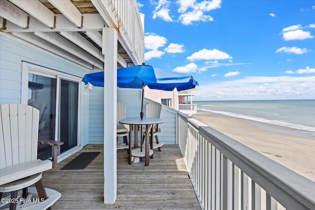 wooden deck with a water view and a beach view