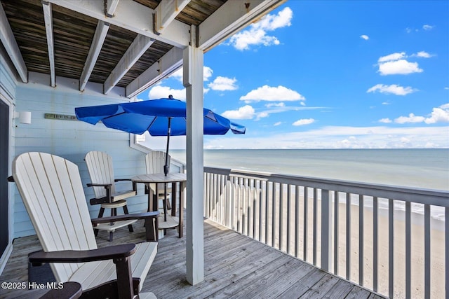 wooden terrace featuring a water view and a view of the beach