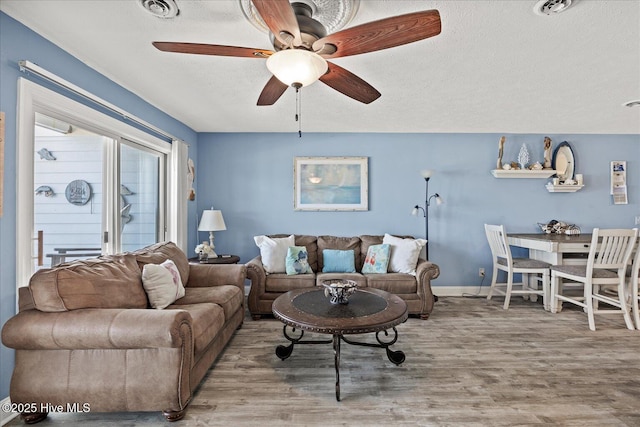 living room featuring hardwood / wood-style floors, ceiling fan, and a textured ceiling