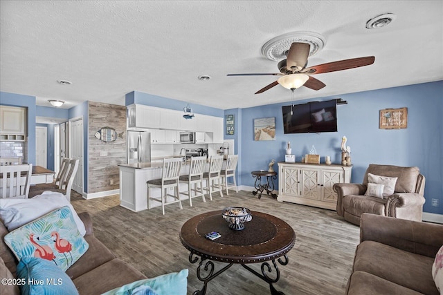 living room featuring ceiling fan, a textured ceiling, and hardwood / wood-style flooring