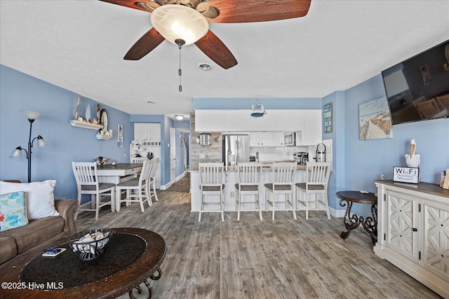 living room featuring ceiling fan, hardwood / wood-style floors, and a textured ceiling