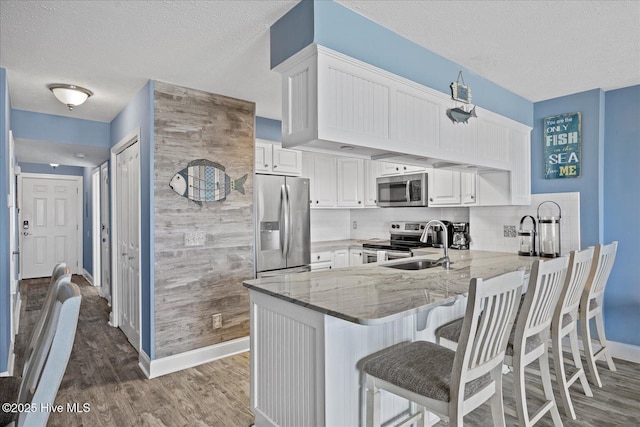 kitchen with white cabinets, appliances with stainless steel finishes, backsplash, and kitchen peninsula