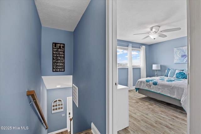 bedroom featuring ceiling fan, a textured ceiling, and light wood-type flooring