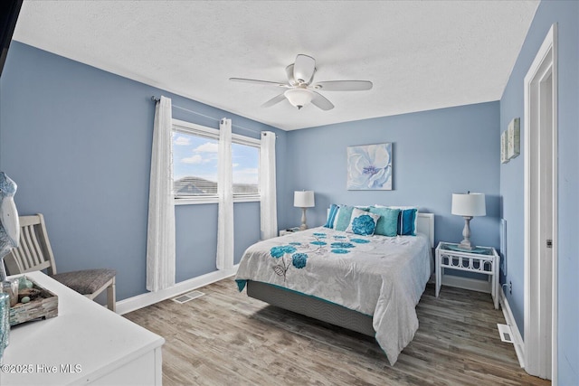 bedroom featuring ceiling fan, hardwood / wood-style floors, and a textured ceiling