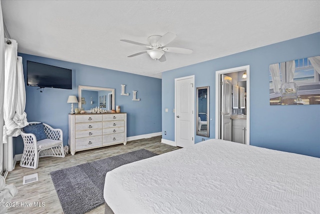 bedroom featuring ensuite bathroom, hardwood / wood-style floors, ceiling fan, and a textured ceiling