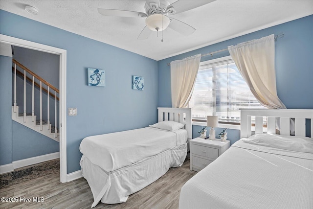 bedroom with a textured ceiling, light wood-type flooring, and ceiling fan