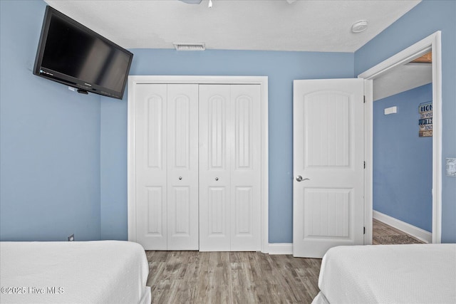 bedroom featuring a closet, a textured ceiling, and light hardwood / wood-style flooring