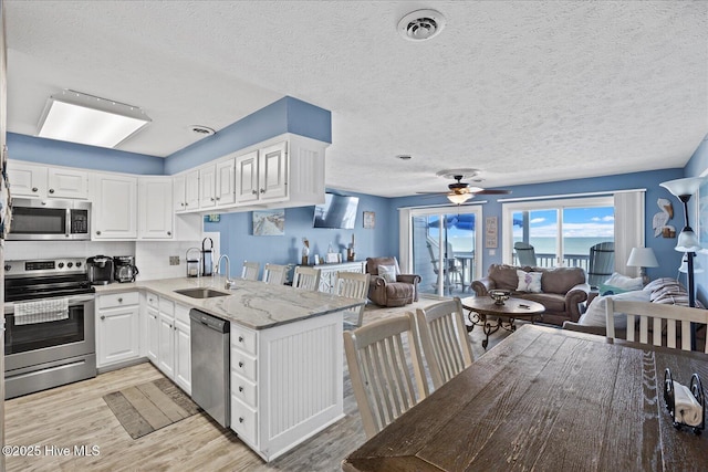 kitchen with backsplash, ceiling fan, appliances with stainless steel finishes, white cabinetry, and kitchen peninsula