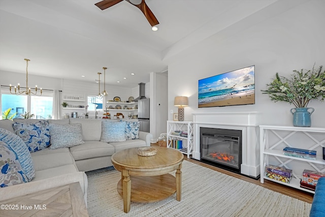 living room with ceiling fan with notable chandelier and light hardwood / wood-style floors