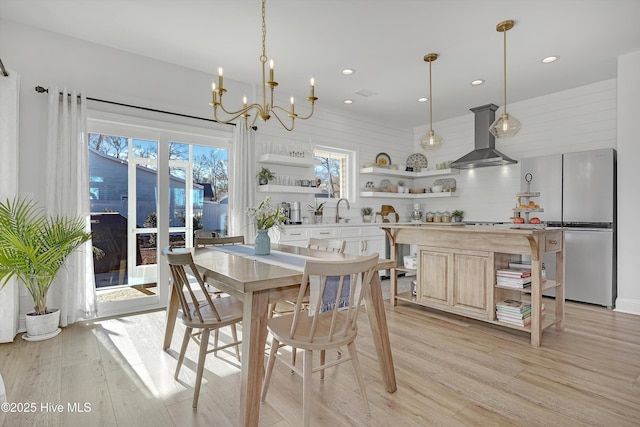 dining room with sink, a notable chandelier, and light wood-type flooring