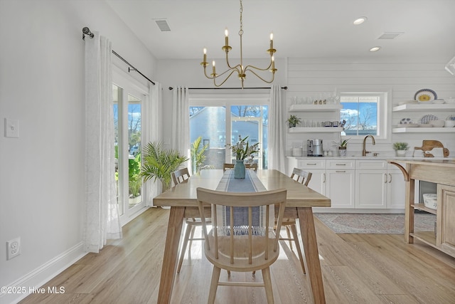 dining area featuring sink, plenty of natural light, a notable chandelier, and light hardwood / wood-style flooring