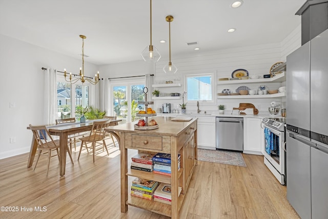 kitchen featuring an inviting chandelier, white cabinetry, hanging light fixtures, and stainless steel appliances