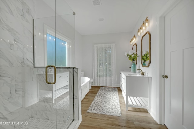 bathroom featuring vanity, wood-type flooring, and plus walk in shower