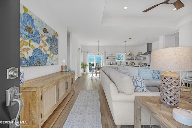 living room with hardwood / wood-style floors and ceiling fan with notable chandelier