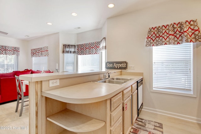 kitchen with black dishwasher, kitchen peninsula, sink, and a wealth of natural light