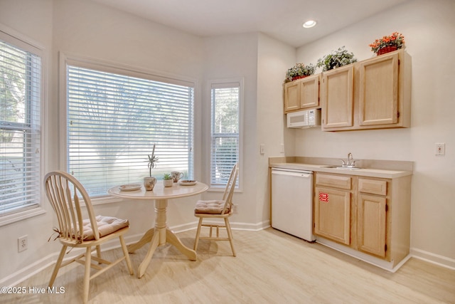 kitchen with light brown cabinets, light wood-type flooring, white appliances, and sink