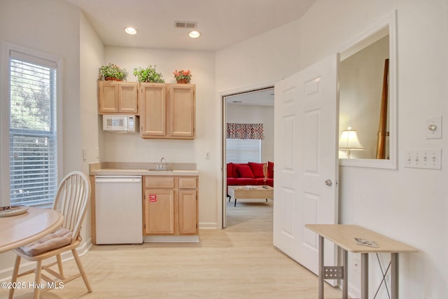 kitchen featuring light wood-type flooring, light brown cabinets, white appliances, and sink