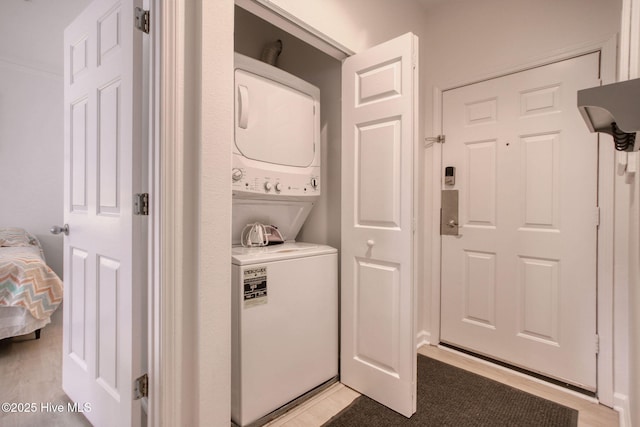 laundry room with stacked washing maching and dryer and crown molding