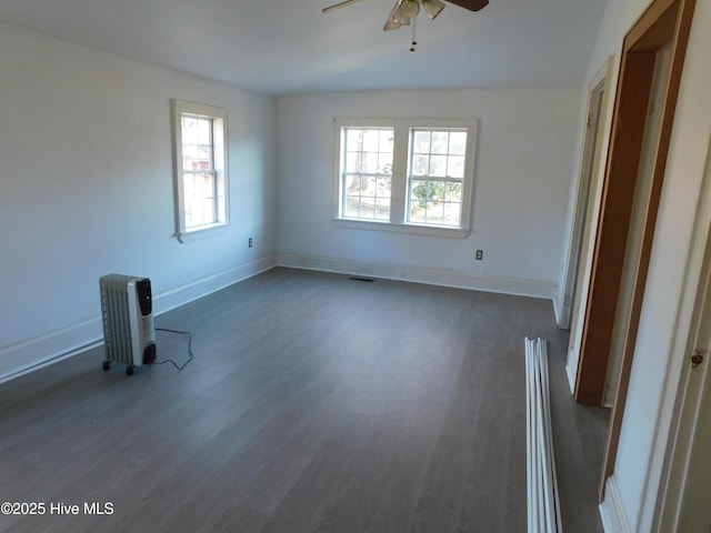 empty room with dark hardwood / wood-style floors, a wealth of natural light, and ceiling fan