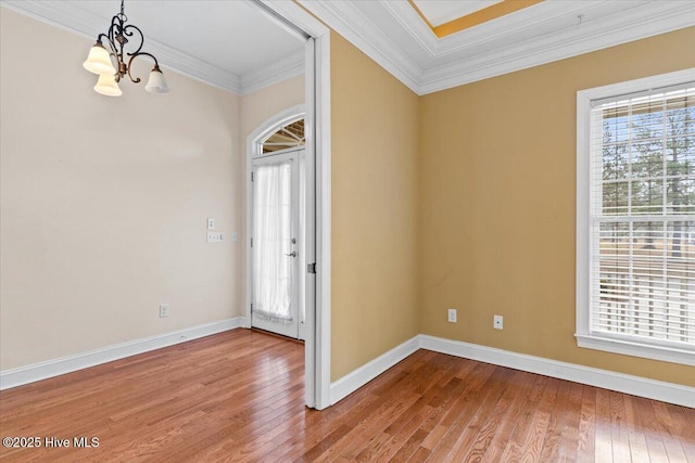 empty room featuring ornamental molding, plenty of natural light, hardwood / wood-style floors, and an inviting chandelier