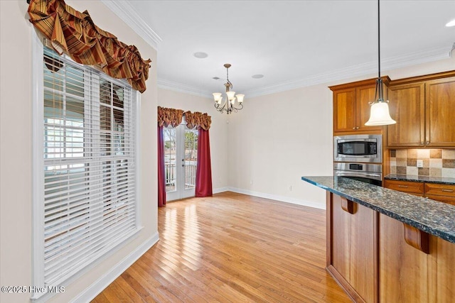 kitchen with hanging light fixtures, crown molding, light hardwood / wood-style flooring, and stainless steel appliances