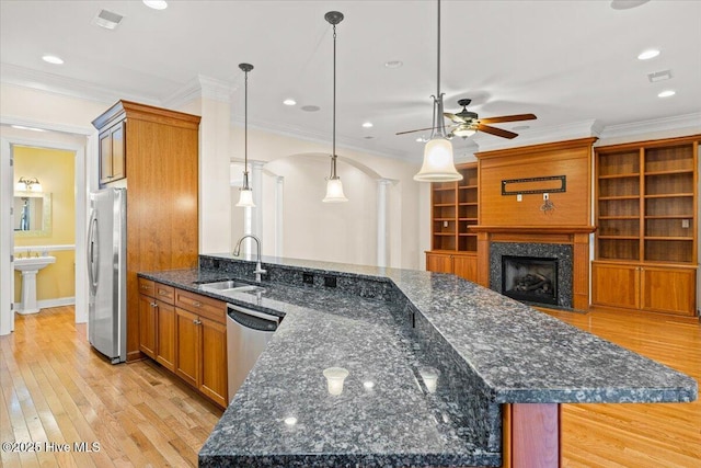 kitchen with pendant lighting, sink, stainless steel appliances, kitchen peninsula, and dark stone counters