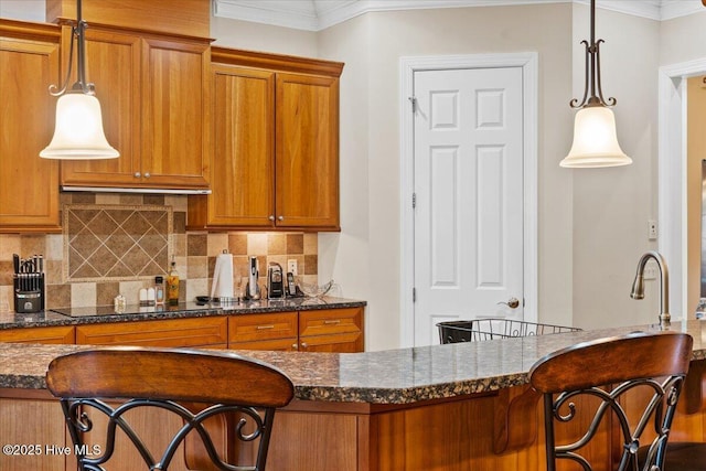 kitchen featuring black electric cooktop, a breakfast bar, hanging light fixtures, and dark stone countertops