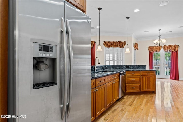 kitchen with hanging light fixtures, stainless steel appliances, sink, and dark stone counters