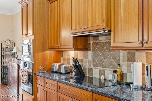 kitchen featuring dark stone countertops, black electric stovetop, crown molding, and backsplash